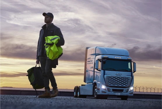 Truck driver carrying a load in front of Hyundai XCIENT Fuel Cell Tractor