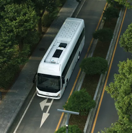 Hyundai UNIVERSE Fuel Cell driving a street between trees